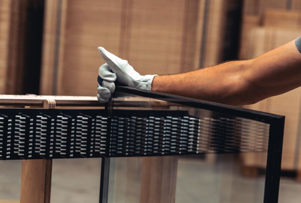 A gloved hand lifting a pane out of its brush-lined slot